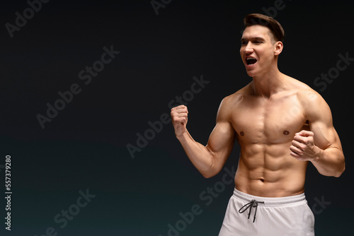 Athletic fitness model screaming and demonstrating muscles while posing