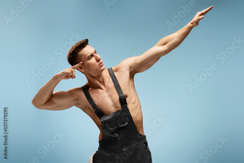 Strong caucasian man in coverall posing over blue background