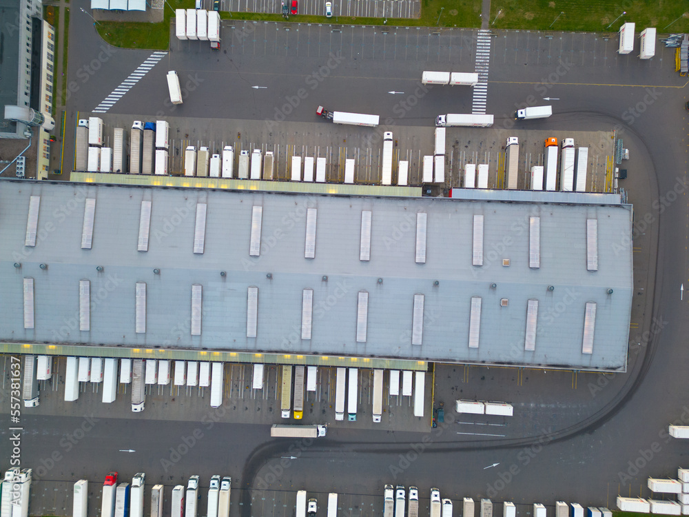 Aerial view of goods warehouse night. Logistics delivery; center in industrial city zone from above. Aerial view of trucks loading at logistic center. View from drone. Aerial view of goods warehouse night. Logistics delivery; center in industrial city zone from above. Aerial view of trucks loading at logistic center. View from drone.
