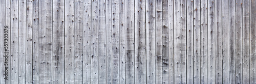 Graue verwitterte Panorama Holzwand aus senkrechten  unterschiedlich breiten Brettern mit starker Maserung