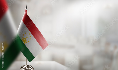 Small flags of the Tajikistan on an abstract blurry background