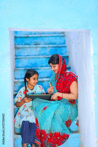 Education concept : Indian rural woman teaching some detail to daughter at home. © Niks Ads
