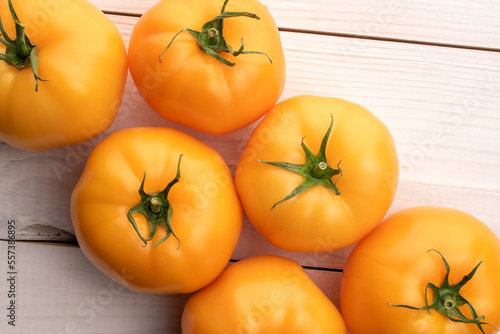 Several organic delicious, juicy tomatoes on a painted white table, top view.