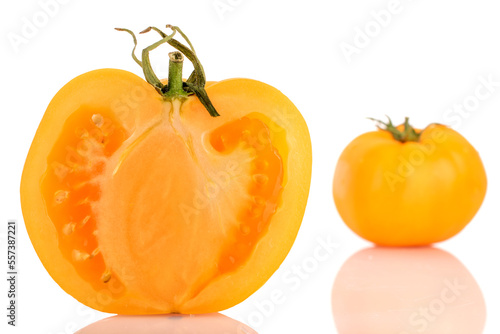 One half, in focus, and one whole natural yellow tomato, close-up, isolated on white.