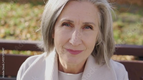 Mature woman with stylish gray hair looking at camera with serious face expression spending time outdoor, feeling social protection, guarantees from the state for pensioners