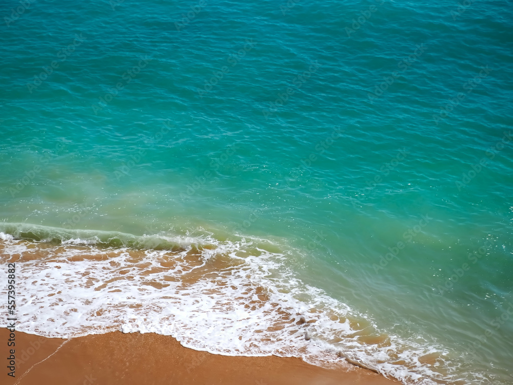 Aerial view of surf in turquoise sea meets red sandy beach