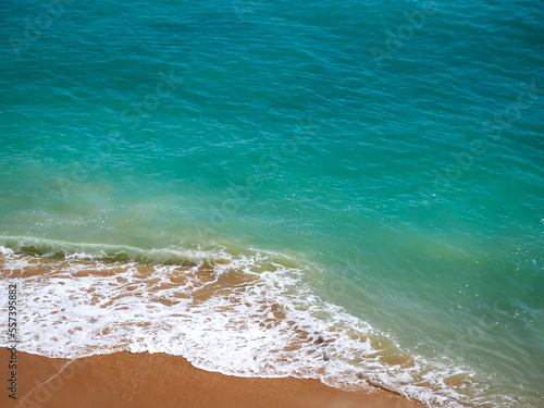 Aerial view of surf in turquoise sea meets red sandy beach