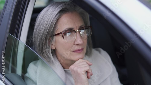 Thoughtful mature woman sitting in car, stuck in traffic jam, life in big city