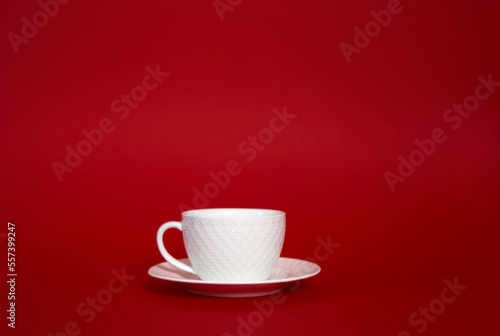 Isolated white cup mug with hot coffee tea on a deep red backround. A beautiful romantic horizontal photo with copy space. Central composition, minimalism style, blank gradient free space for text