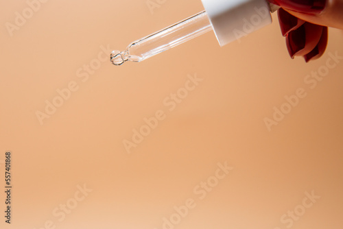 Woman hand holding pipette with collagen moisturizing hyaluron serum and drops the clear serum photo