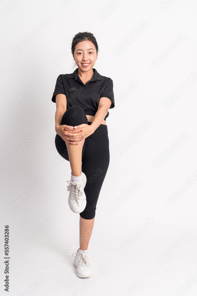 woman standing doing leg stretch by lifting and holding legs forward on isolated background