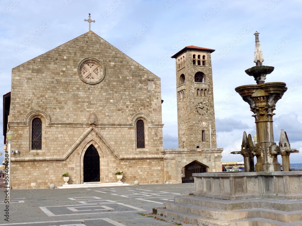 Obraz premium Fountain in front of a church on the quay at Rhodes Harbor on Rhodes, Greece