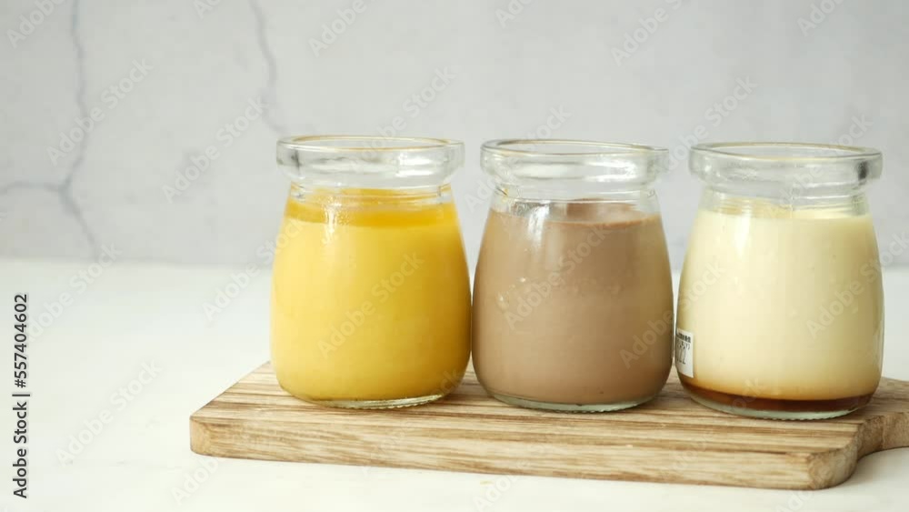 Caramel, chocolate and mango pudding in a glass jar on pink background Caramel, chocolate and mango pudding in a glass jar on pink background