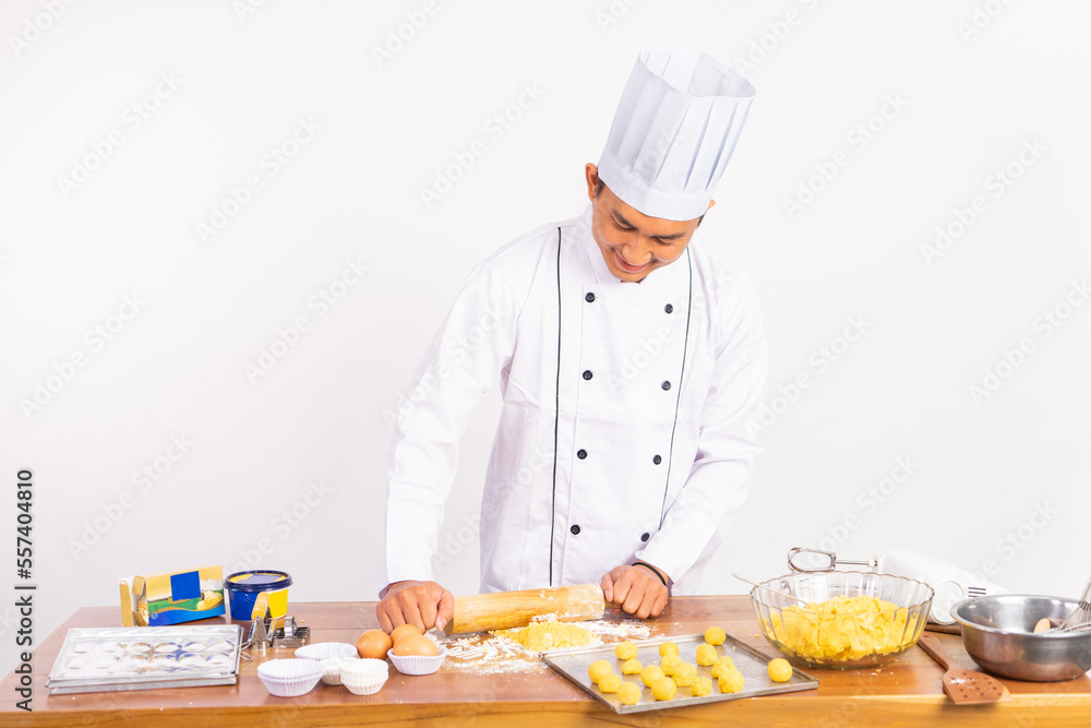 male chef wearing chef jacket using wooden rolling pin on table on isolated background male chef wearing chef jacket using wooden rolling pin on table on isolated background