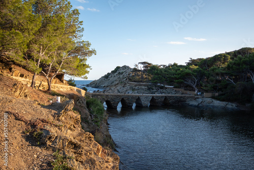 Puente hacia una isla en el pueblo de la Costa Brava de Cadaqués rodeada del azul mar Mediterráneo con el sol bañándolo todo.