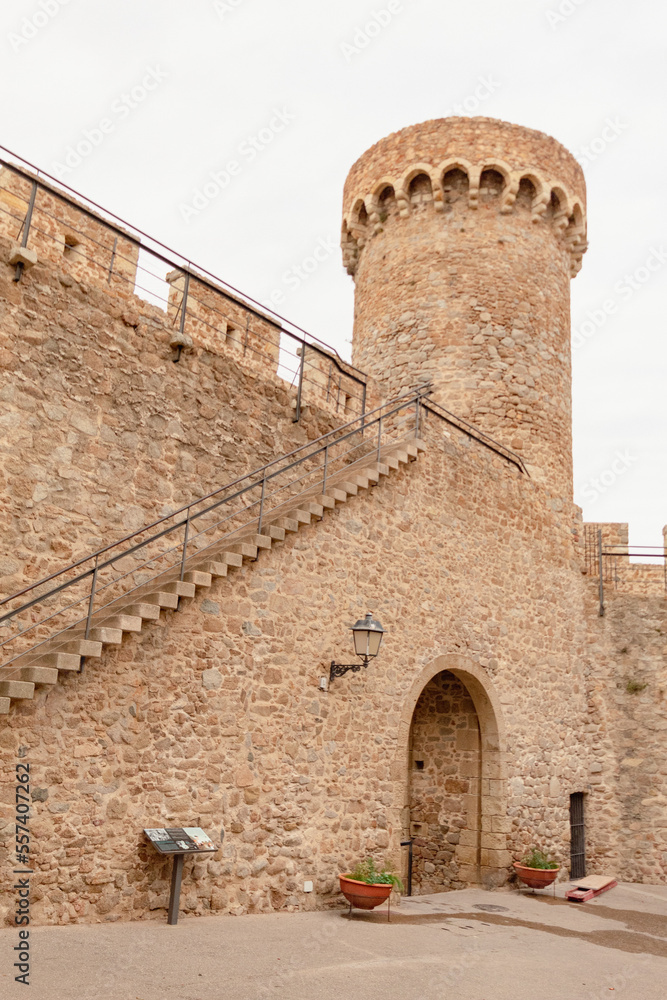 Escaleras para subir a la muralla del Castillo Vila Vella de Tossa de Mar en Girona plantas para decorar la entrada al pueblo bajo un antiguo arco de piedra.