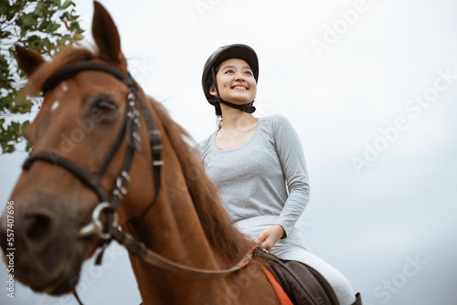 beautiful woman equestrian athlete practicing horse riding on outdoor background