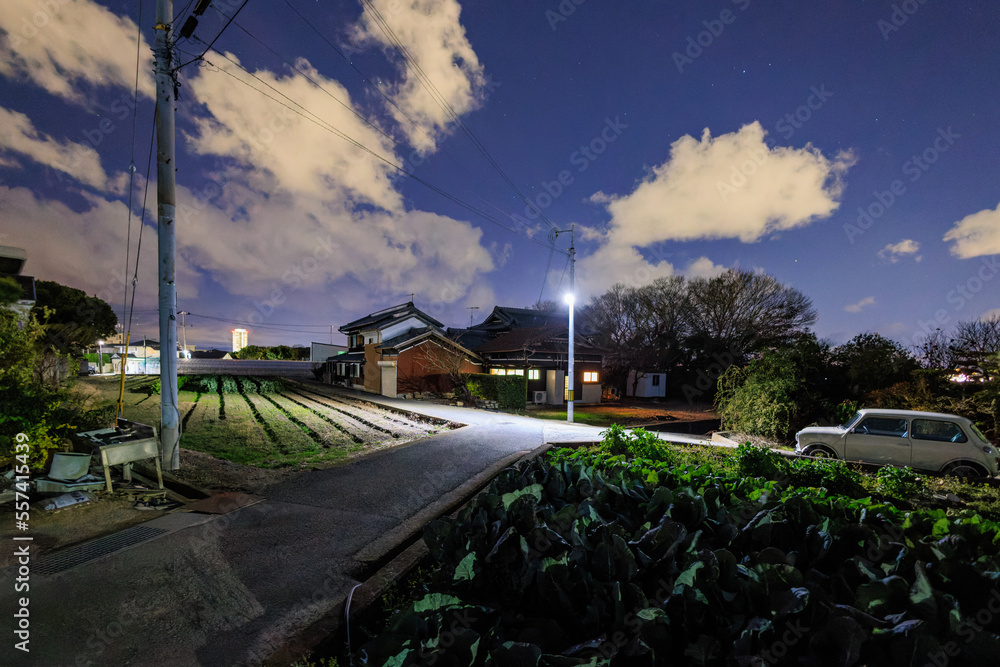 Japanese house and small fields with white clouds in dark blue sky at night