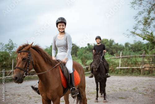 female athlete riding horse to train with male athlete on outdoor background
