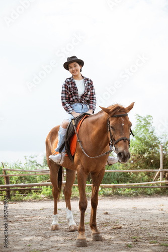 woman in cowboy hat smiling sitting on horse at ranch