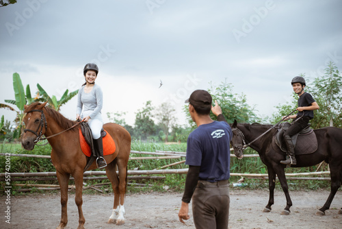 two equestrian athletes riding horses listening to trainer standing guide on outdoor background © Odua Images