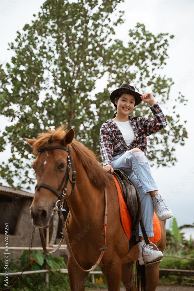 beautiful cowboy girl smiling sitting on horse on outdoor background