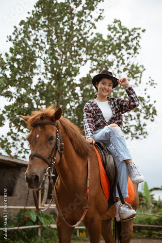 beautiful cowboy girl smiling sitting on horse on outdoor background