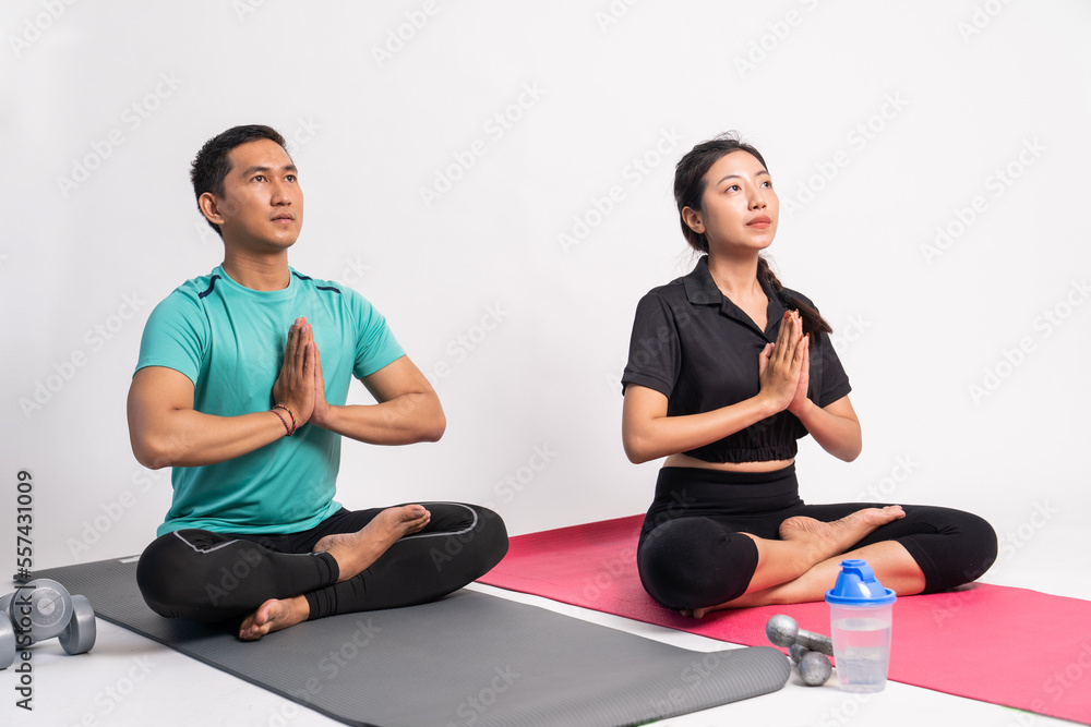 man and woman sitting on mat with hands in front of chest while yoga on isolated background man and woman sitting on mat with hands in front of chest while yoga on isolated background