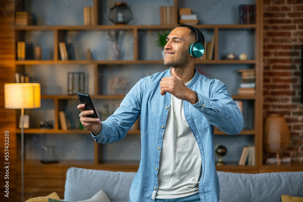 Obraz premium Cool young man dancing and listening to music at home