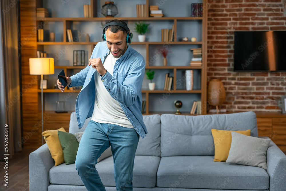 Fototapeta premium Young man in headphones dancing at home