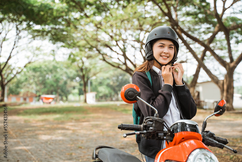 Student girl tightens helmet strap when going to ride a motorbike