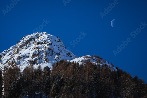 The mountains and the nature of val forno and val Bregaglia with fresh snow on the trees, lots of cold and a beautiful sun, near the village of Maloja, Switzerland - December 2022. photo