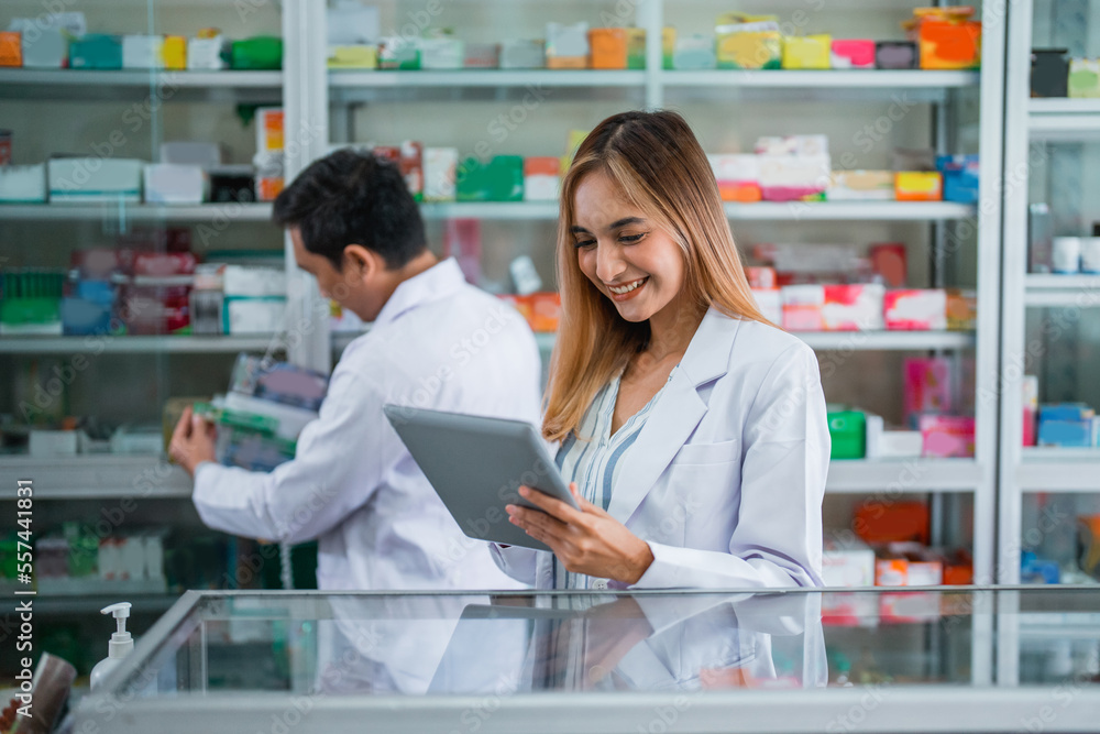 Asian female pharmacist in uniform working using digital tablet in pharmacy