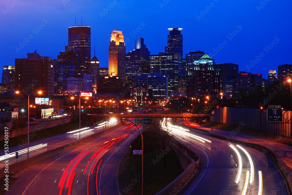 Traffic rushes along a highway to and from the downtown city skyline of Minneapolis, Minnesota at night Traffic rushes along a highway to and from the downtown city skyline of Minneapolis, Minnesota at night