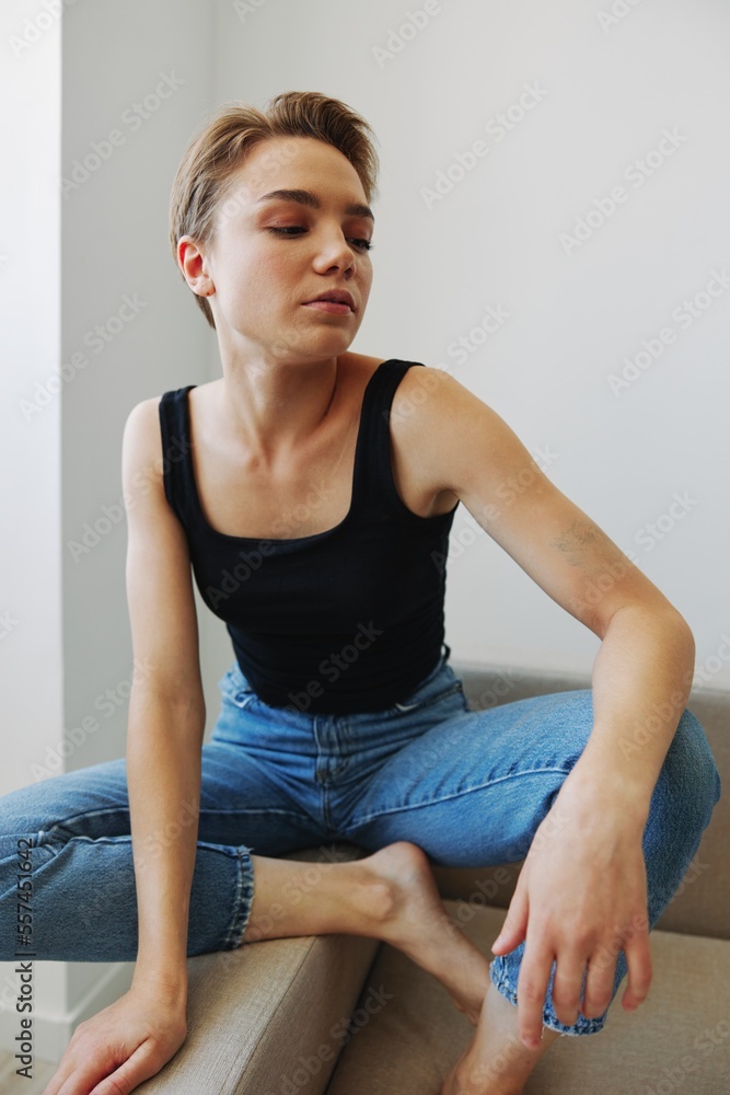Young woman with short haircut hair having fun at home on the couch smile and happiness, vacation at home, natural posing without filters, free copy space