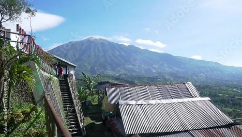 Panoramic view of Mount Merapi and Mount Merbabu with rice fields below and the blue sky behind them from Ketep Pass, Magelang, Central Java, Indonesia photo