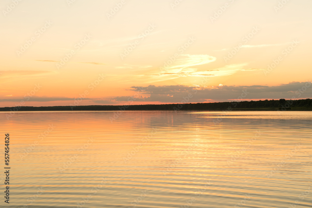 Sunset on the lake, the pink-gold sky is reflected in the water.