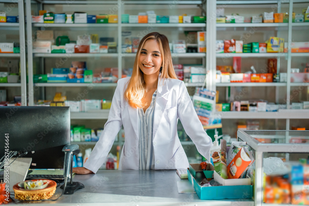 beautiful asian female pharmacist in uniform smiling at the camera at the pharmacy