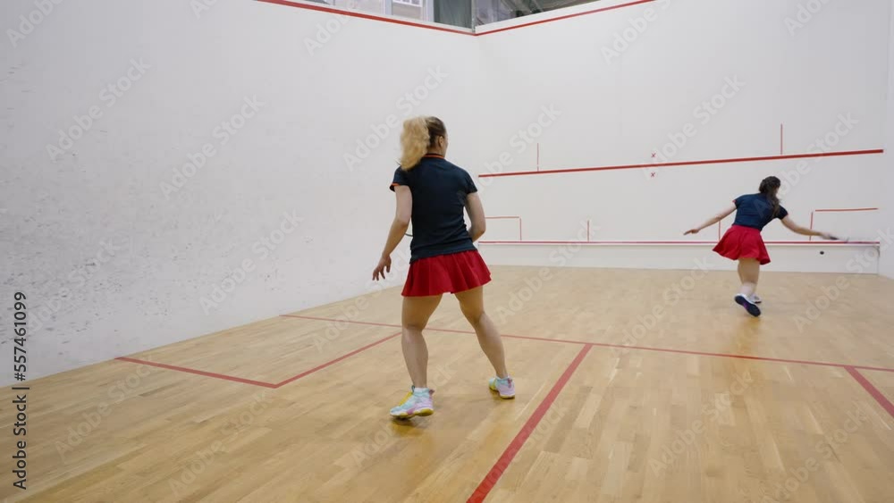 Couple of young women plays squash on four-walled court Couple of young women plays squash on four-walled court