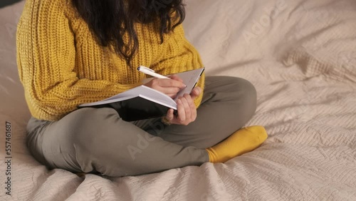 unrecognizable woman makes notes in a notebook. Hand writes.. Woman makes plans for the future, doing academic research preparing for exam coursework studying at home photo