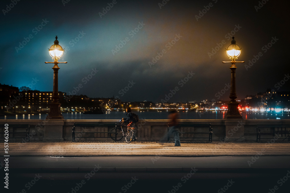 Cyclist stops on a bridge at night to enjoy the view of Copenhagen, Denmark 