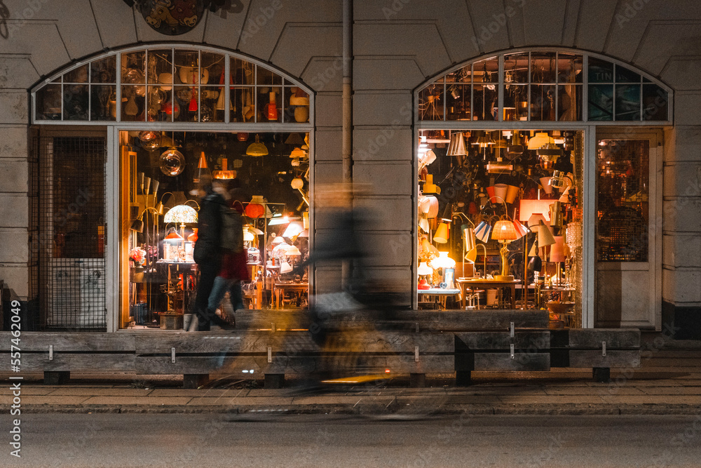 A cyclist rides past a lamp store in Copenhagen, Denmark at night 
