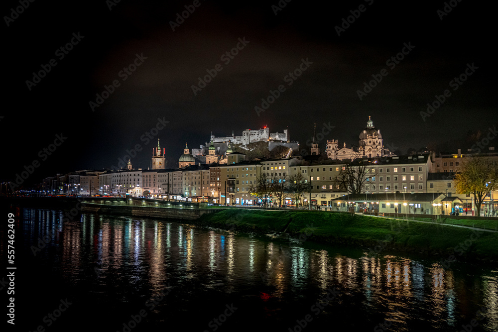 Salzburg old town with Fortress Hohensalzburg in the background at night with lights from the banks of the Salzach river in Austria 