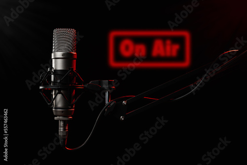 Professional large diaphragm microphone for podcast on black background backlighted with red colour photo