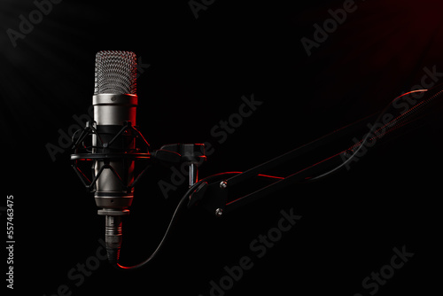 Professional large diaphragm microphone for podcast on black background backlighted with red colour