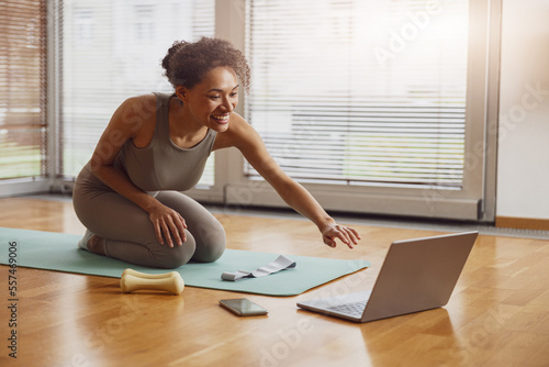 Free Download Afro american sporty woman sit on floor and preparing for online fitness class from home - GFXLoad