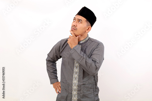 Thoughtful asian muslim man standing while thinking something. Isolated on white background