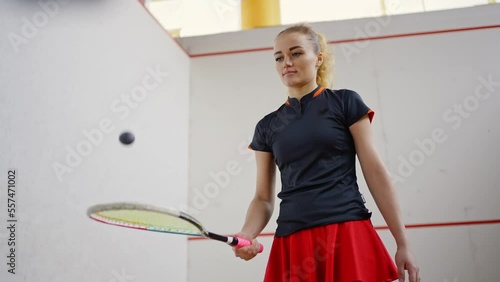 Blonde squash player in sportswear exercises on court photo