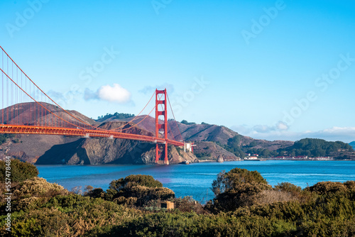View of historic Golden Gate Bridge over beautiful San Francisco Bay with mountains and blue sky in the background during sunny day