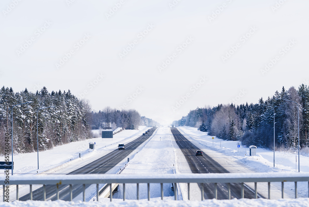 Winter highway. Asphalt road through a snowy forest. Car driving on a heavy winter road. Snowy and frozen road in winter landscape. Winter highway. Asphalt road through a snowy forest. Car driving on a heavy winter road. Snowy and frozen road in winter landscape.